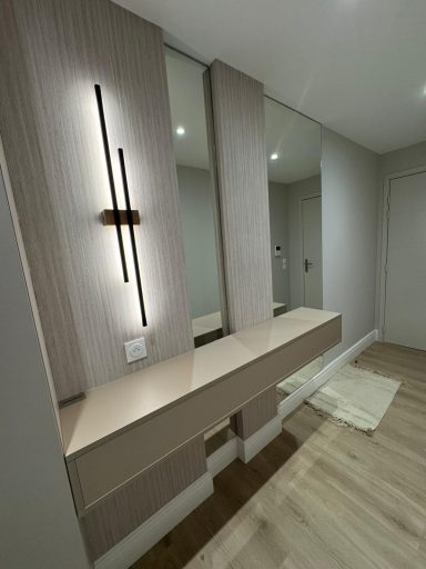 Meuble de salle de bain moderne avec miroir et éclairage. Sol en bois clair.